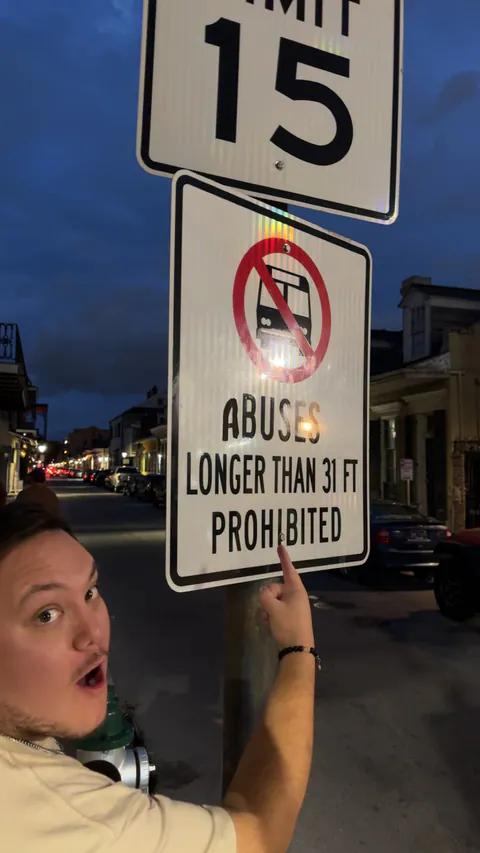 A man makes a shocked face and points at a street sign altered to read Abuses Longer Than 31 Ft Prohibited.