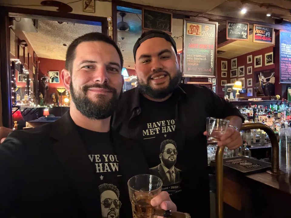 Two bearded friends in Have You Met Haws? shirts smile in a bar selfie, drinks in hand.